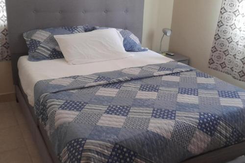 a bed with a blue and white quilt on it at 1 Bed Apartment Sleeps 4 with Free Parking in Kasoa