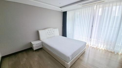 a bedroom with a white bed and a large window at 팔레드시즈 콘도- Pale de CZ Condo in Busan