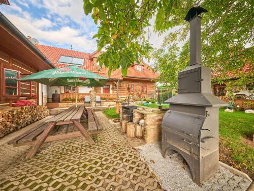 a outdoor grill with a picnic table and a picnic table with an umbrella at Holiday Home Růžovka by Interhome in Úhlejov