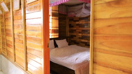 a small bedroom with a small bed in a wooden cabin at Homstay Páo Ấm Mai in Tát Lá