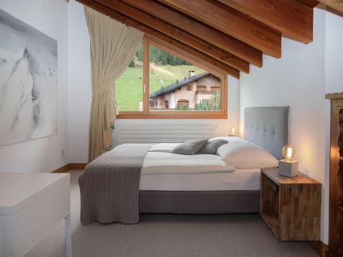 a bedroom with a large bed and a window at Apartment Chesa Vadret 12 by Interhome in Pontresina