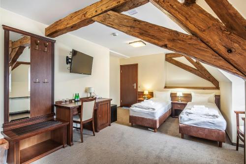 a bedroom with two beds and a desk and a tv at Pałac Łagów in Zgorzelec