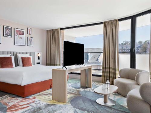 a hotel room with a bed and a flat screen tv at Mercure Amiens Cathédrale in Amiens