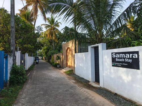 a street with a fence and a sign that reads santa beachstay at Samara Beach Stay in Weligama