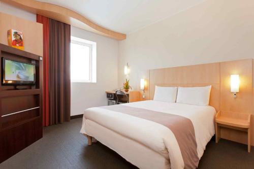 a hotel room with a large bed and a television at Ibis Malabo in Ciudad de Malabo