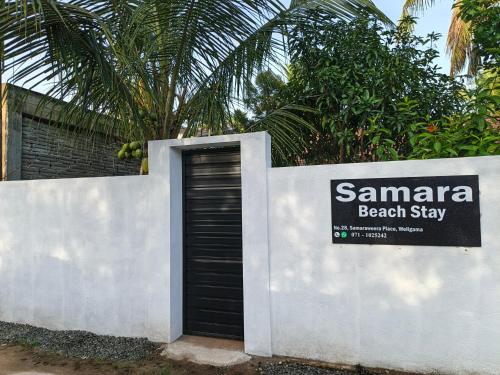 a door in a white wall with a sign on it at Samara Beach Stay in Weligama