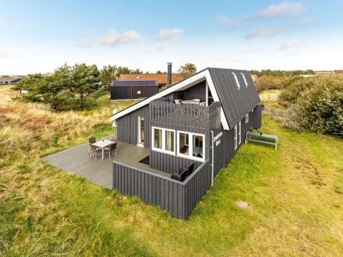 una casa nera con un ponte su un campo di Holiday Home Casandra - 600m from the sea by Interhome a Fanø