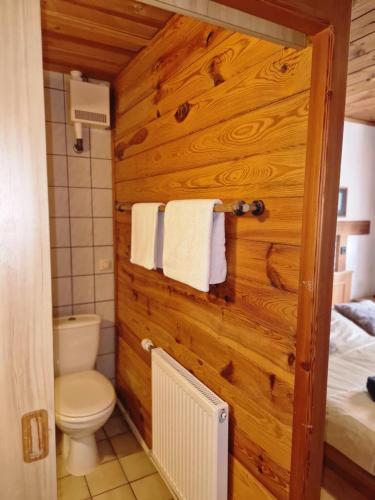 a bathroom with a wooden wall with a toilet and towels at Gasthof Zaunerhof - Hotels en Appartementen in Grünau im Almtal