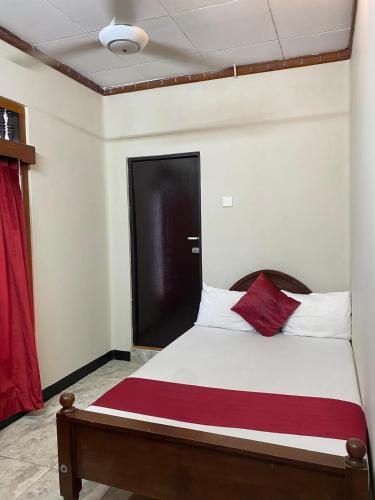 a bed in a room with a red curtain at MercuryFM 109 Guest House - Jaffna Temple road 77 in Jaffna