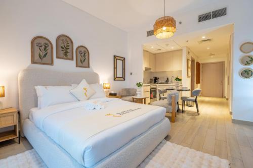 a bedroom with a large white bed and a kitchen at Relaxed Luxe Studio - Elegant City Escape in Abu Dhabi