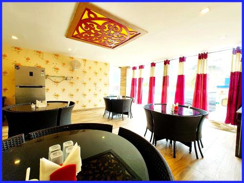 a restaurant with tables and chairs and red curtains at Rooftop Sea View Boutique Shivangi Hotel Near Jagannath Temple 1400m - Restaurant- Lift and Free Parking Facilities - Fully Air Conditioning Premium Rooms- Best Sea Beach Hotel In Puri in Puri