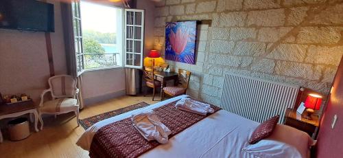 a bedroom with a bed and a large window at Logis Hôtel Le Bussy in Montsoreau