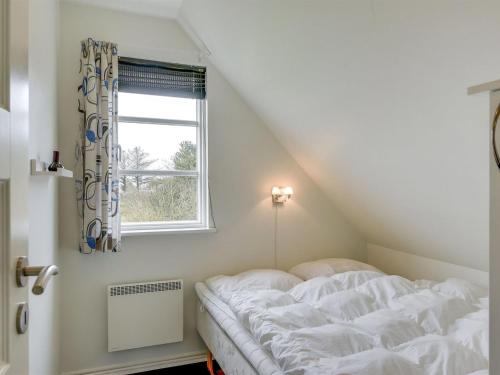 a white bed in a room with a window at Holiday Home Benita - 400m to the fjord by Interhome in Skjern