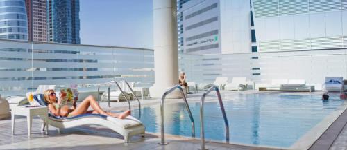 a woman sitting in a chair next to a swimming pool at Byblos Hotel in Dubai