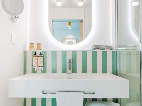 a bathroom with a sink and a mirror at Mercure Président Biarritz Plage in Biarritz
