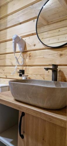 a bathroom sink with a mirror on a wooden wall at Nice House in Maidan Village