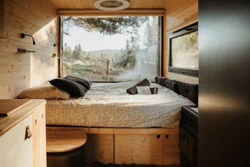 a bedroom in a tiny house with a large window at Refuge panoramique en Haute-Loire in Saint-Julien-Molhesabate