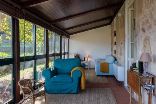 a living room with a blue chair and windows at Quinta da Janeca in Vila Pouca de Aguiar