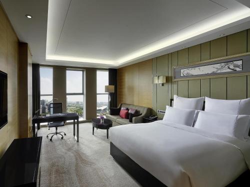 a hotel room with a large bed and a desk at Pullman Wuxi New Lake in Wuxi