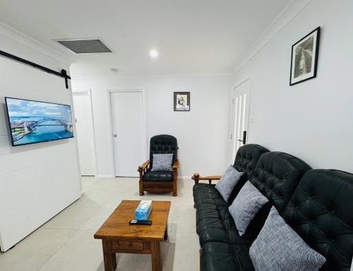 a living room with a black couch and a table at Bran new home with ducted AC to stay in Sydney in Oakhurst