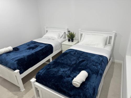 two beds in a white room with towels on them at Bran new home with ducted AC to stay in Sydney in Oakhurst