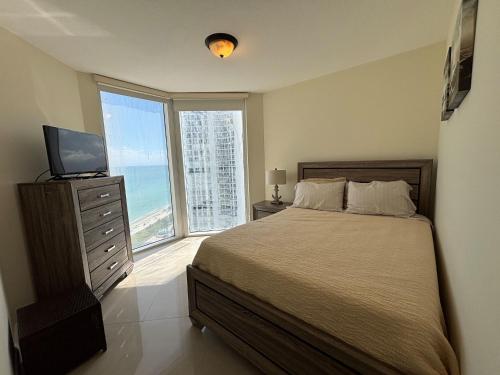 a bedroom with a bed with a television and a window at Luxurious 2BD Condo with Direct Ocean Views & Resort Pool in Sunny Isles in Sunny Isles Beach