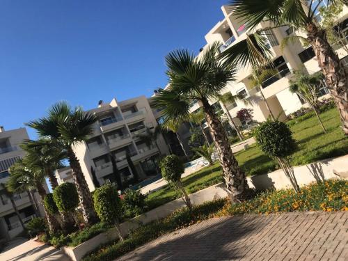a row of palm trees in front of a building at Best appartement pools view at Mansouria in Pont Blondin