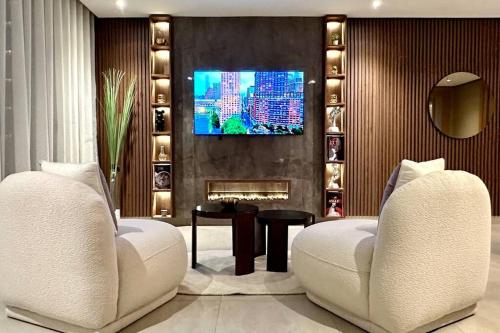 a living room with two white chairs and a tv at State of Peace in Marina - By AppartAli in Casablanca-Port