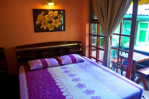 a bedroom with a bed with purple sheets and a window at Pailin Guest House in Bangkok
