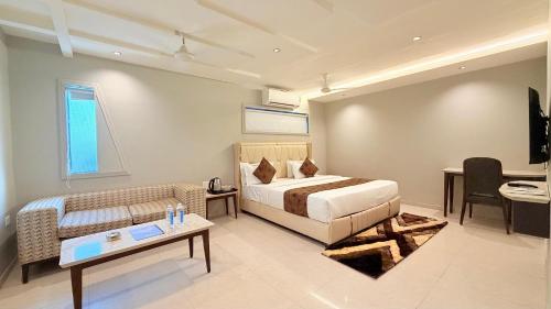 a bedroom with a bed and a couch and a table at Hotel Nova Vista in Rajkot