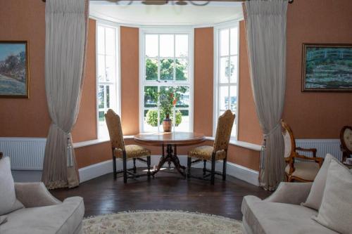Una sala de estar con mesa y sillas y ventanas. en Hill House, Georgian period house, sleeps 17, en Cashel