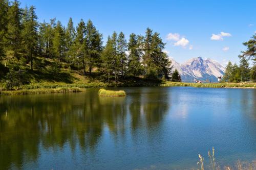a lake with trees and mountains in the background at Maison Rosamunda - Happy Rentals in Oulx