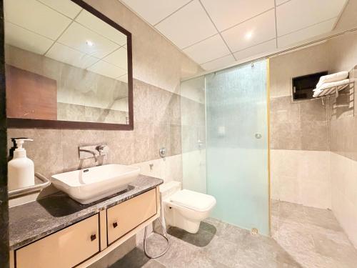 a bathroom with a sink and a toilet and a shower at Hotel Nova Vista in Rajkot