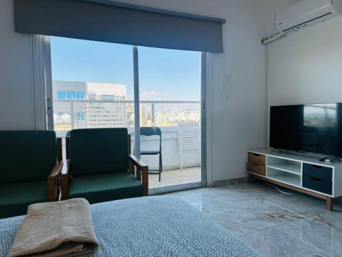 a bedroom with a bed and a flat screen tv at Central Rooms, 500m to Larnaca Marina in Larnaka