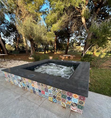 a hot tub in a park with trees in the background at Villa Kalorama-private pool & Hot Tub in San Vito dei Normanni