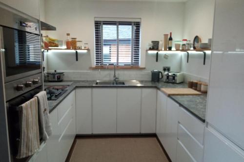 a kitchen with white cabinets and a sink at 2 Bed Cottage Sleeps 4 -Private Garden -Pets Okay in Blairgowrie