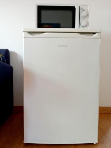 a microwave sitting on top of a white refrigerator at Casas Dona Zi in Vila Nova de Milfontes