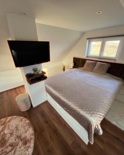 a bedroom with a bed and a flat screen tv at Diófás Ház in Siklós