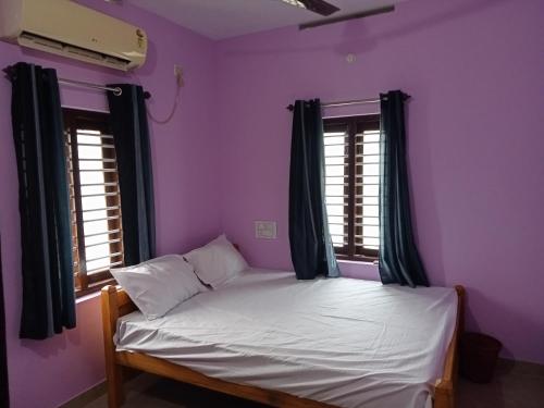 Cama en habitación con paredes y ventanas de color púrpura en Ashabhavan, en Varkala