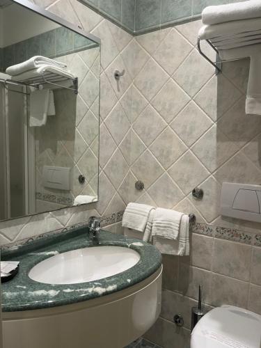 a bathroom with a sink and a toilet and a mirror at Mare Home Brunch&Beauty - Adults Only in Cesenatico