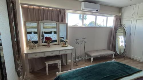 a bedroom with a dressing table and a mirror at The Pearl in the Winelands in Paarl