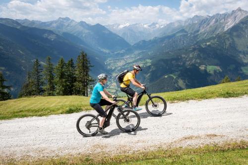 Dos personas montando en bicicleta por una carretera de montaña en Alpengasthof Pichler, en Sankt Veit in Defereggen