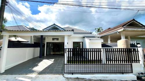 a white house with a gate in front of it at Baiyok Villas near Kathu Waterfall in Ban Huai Luk (1)