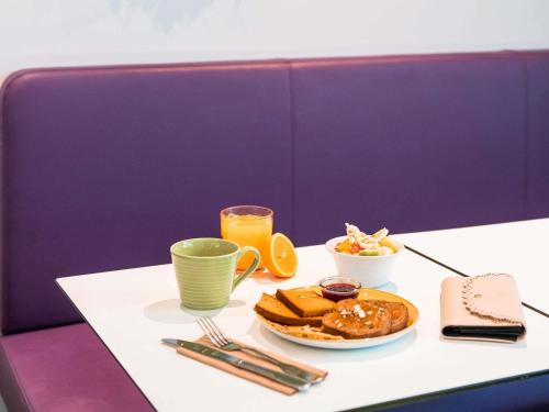 a table with a plate of food and a glass of orange juice at ibis Styles Montbéliard in Montbéliard