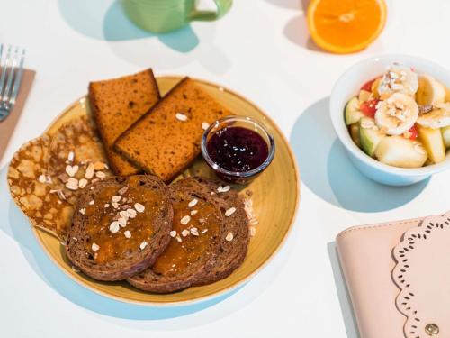 un plato de comida con panqueques y un bol de fruta en ibis Styles Montbéliard, en Montbéliard