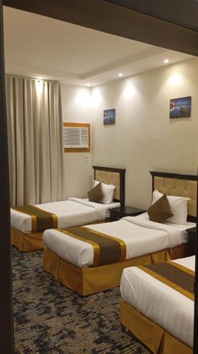 a hotel room with three beds in a room at شقق ريحانة أبها للشقق المخدومة in Abha
