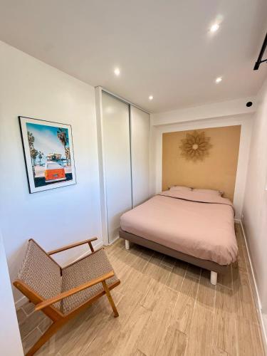 un dormitorio con una cama y una silla en Charmant 2 pièces piscine plage & 15 min de Cannes, en Mandelieu-la-Napoule
