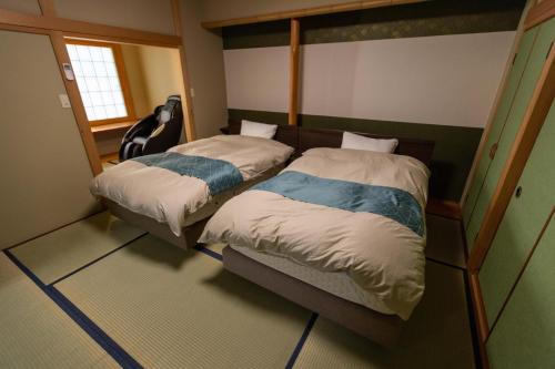 2 camas individuales en una habitación con espejo en 信夫温泉青州, en Fukushima