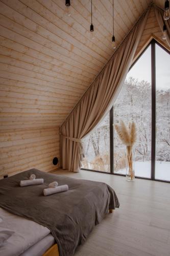 a bedroom with a bed and a large window at Domki Momenty in Słajszewo