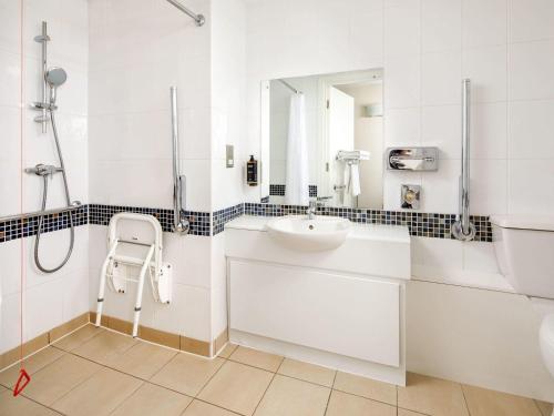 a white bathroom with a sink and a shower at Mercure Glasgow City Hotel in Glasgow